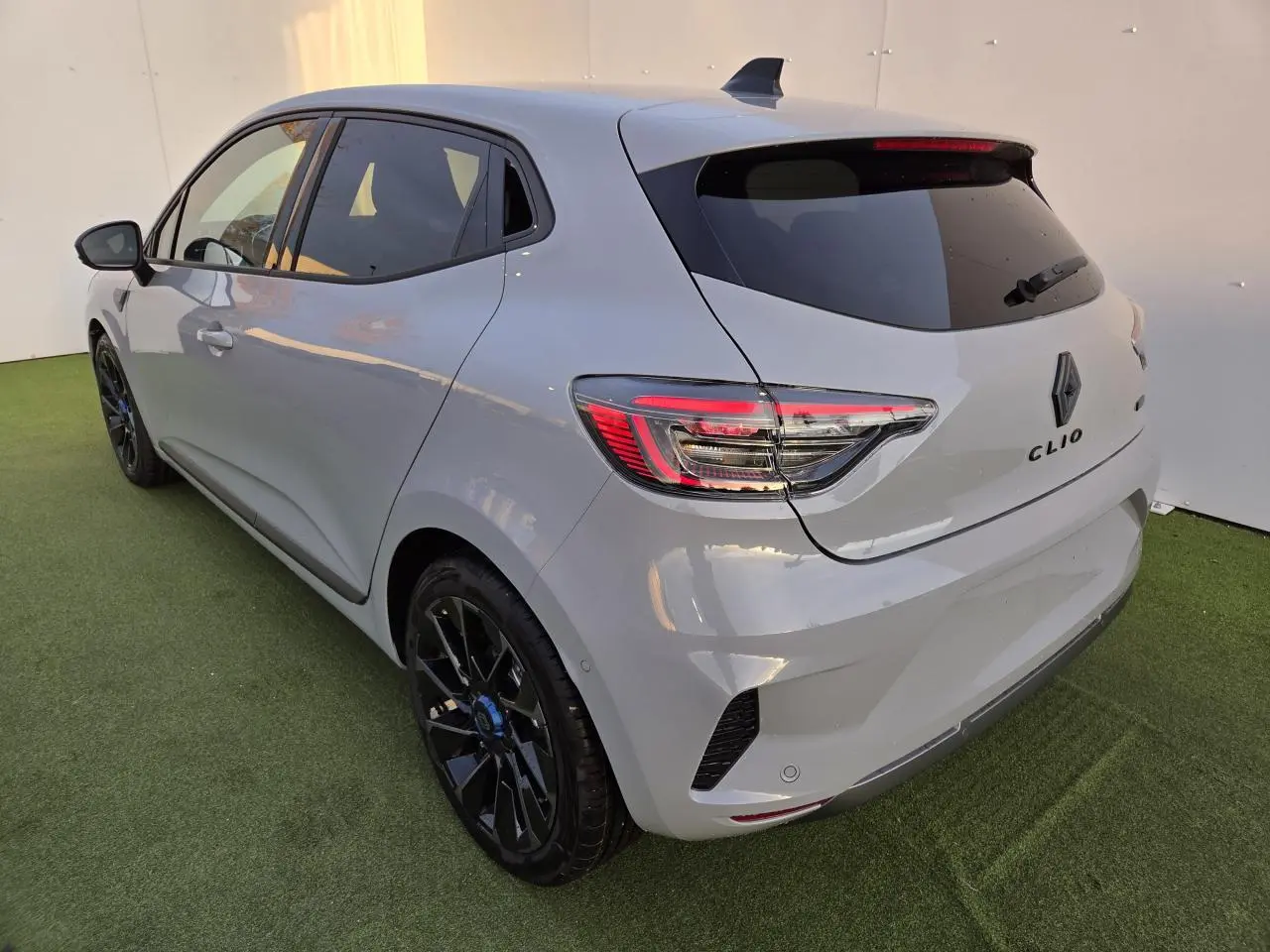 Vue 3/4 arrière droite d'une Renault Clio 2025 gris Rafale avec jantes noires et feux arrière LED en C.