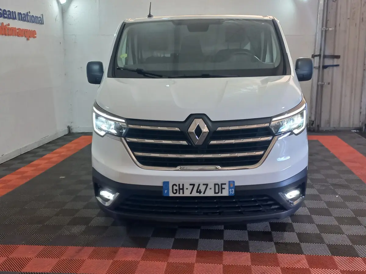 Vue frontale d’un Renault Trafic Fourgon blanc 2022 avec phares LED allumés dans un garage.