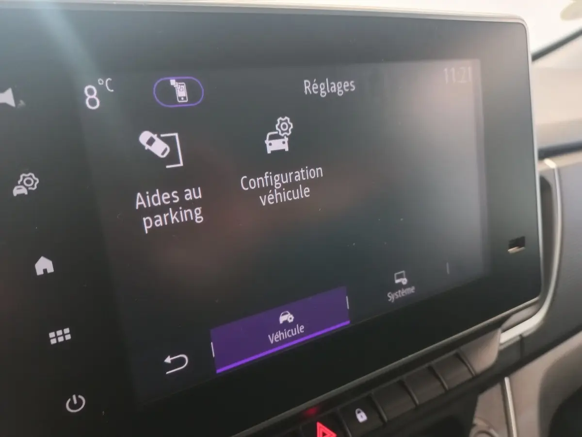 Écran tactile central du Renault Trafic Fourgon blanc, affichant les réglages d'aides au parking et configuration véhicule.