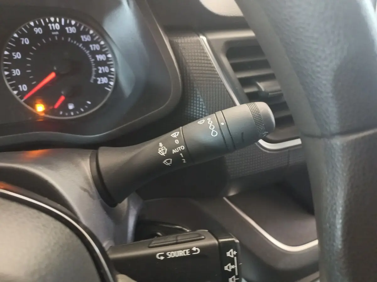 Gros plan sur la commande d’essuie-glace et le tableau de bord noir du Renault Trafic Fourgon blanc, vue côté conducteur.