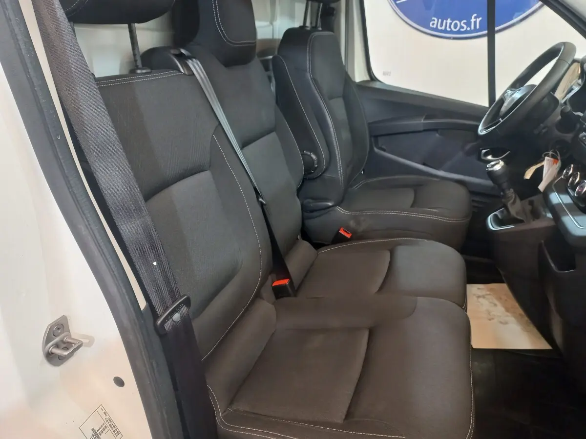 Vue intérieure côté conducteur du Renault Trafic Fourgon 2022, sièges noirs et volant multifonctions visible.