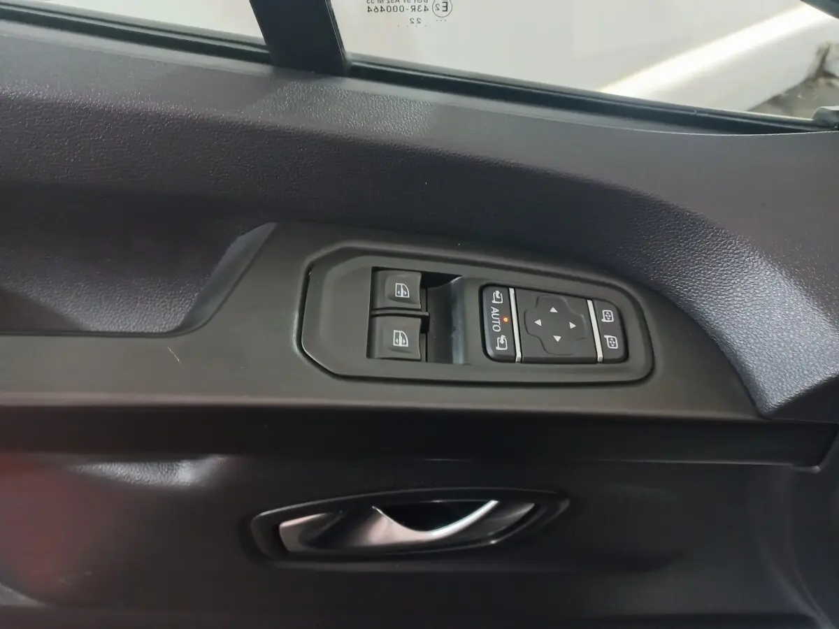 Gros plan sur la commande des vitres et rétroviseurs côté conducteur du Renault Trafic Fourgon blanc, intérieur noir.