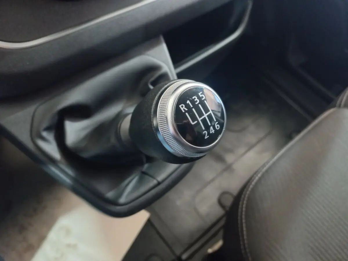 Gros plan sur le levier de vitesses manuel noir et chrome du Renault Trafic Fourgon blanc, intérieur côté conducteur.