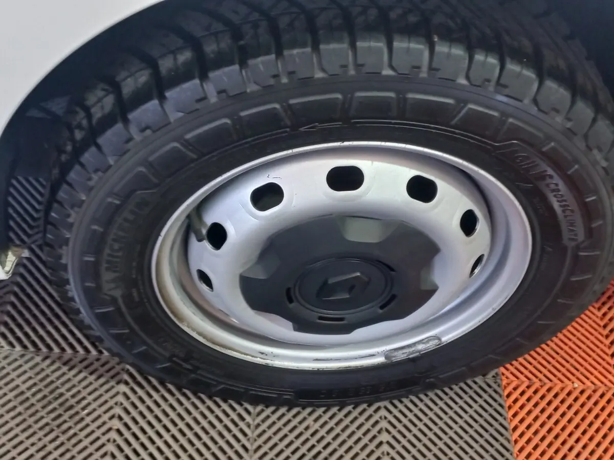 Gros plan sur la roue avant gauche du Renault Trafic Fourgon blanc, jante acier avec logo Renault central.