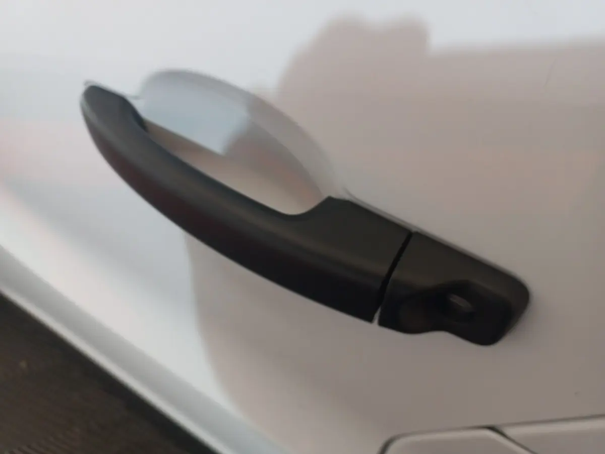 Poignée de porte noire en gros plan sur la portière blanche d’un Renault Trafic Fourgon 2022.