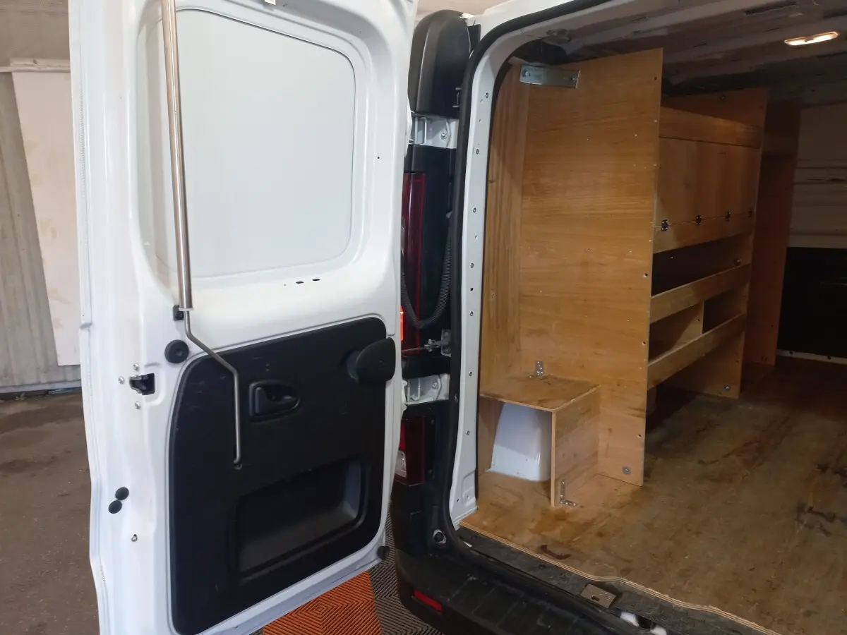 Vue arrière droite du Renault Trafic Fourgon blanc 2022 avec porte ouverte montrant l'aménagement bois intérieur.