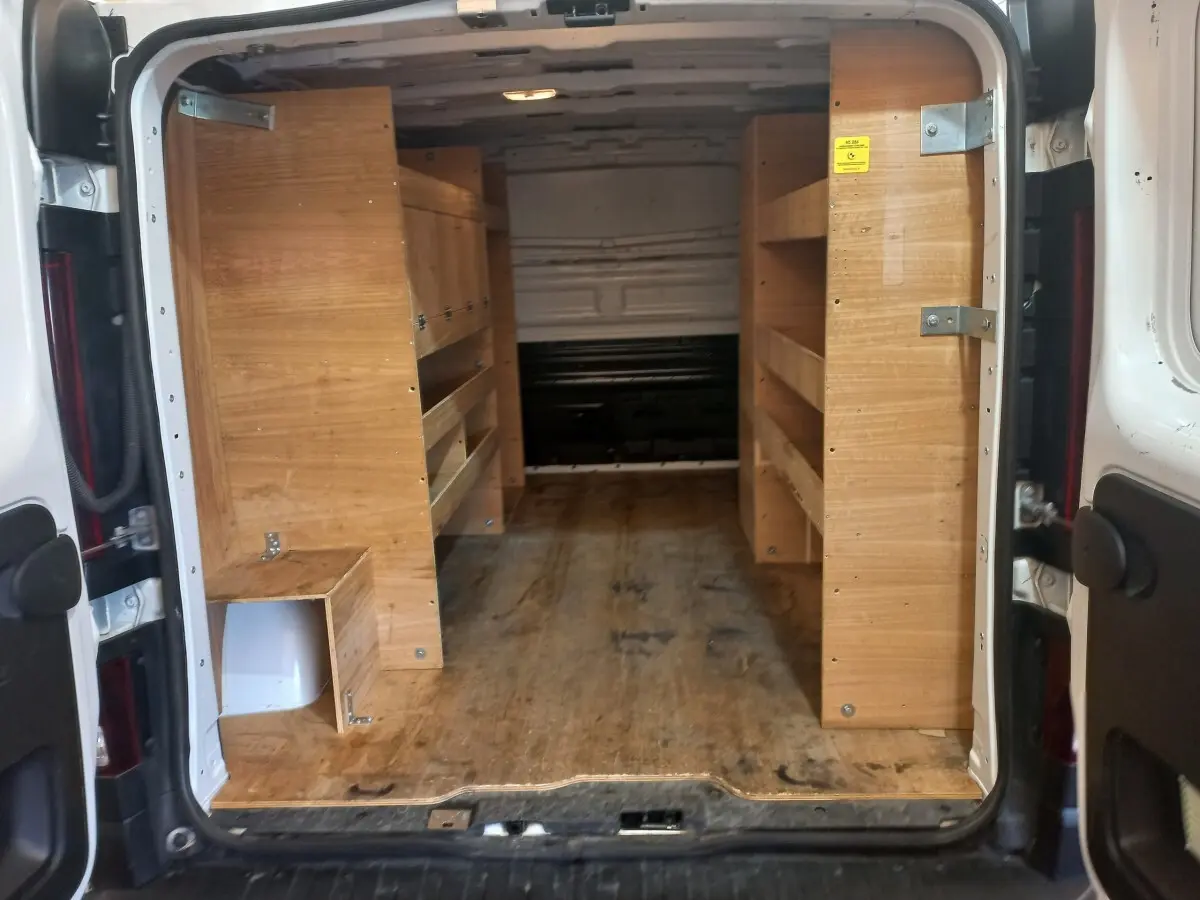 Vue arrière ouverte du Renault Trafic Fourgon blanc de 2022, montrant l'intérieur équipé de rangements en bois.