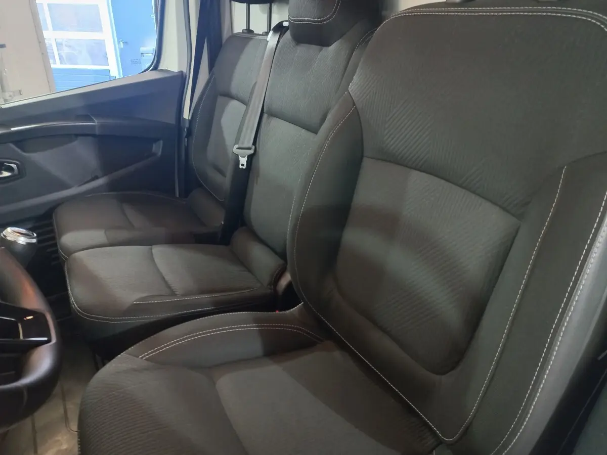 Vue intérieure côté droit des sièges avant noirs du Renault Trafic Fourgon blanc, avec ceinture de sécurité visible.