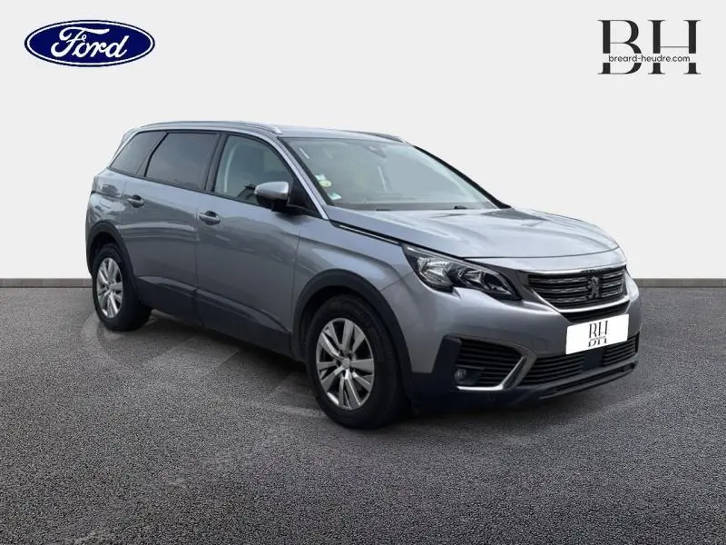 Peugeot 5008 gris Artense vue 3/4 avant droit, SUV familial avec barres de toit et jantes alu.