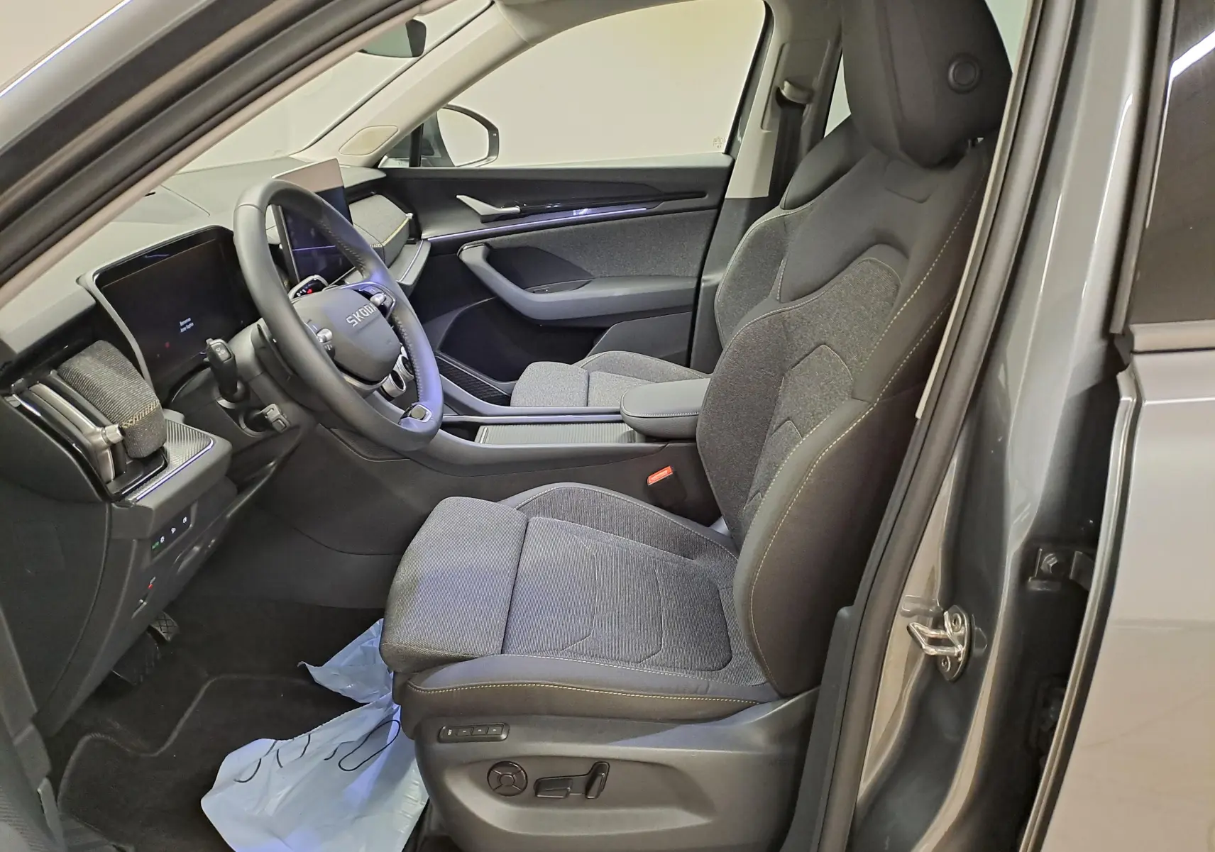 Vue intérieure côté conducteur du Skoda Kodiaq gris graphite 2025, sièges tissu gris et tableau de bord moderne.