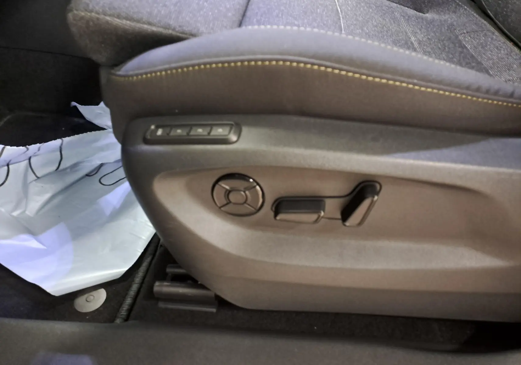 Gros plan sur les commandes de réglage électrique du siège avant côté gauche d’un Skoda Kodiaq gris graphite.