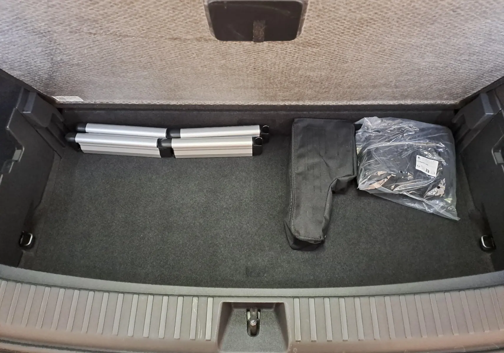 Coffre ouvert d'un Skoda Kodiaq gris graphite, vue de dessus montrant un rangement avec accessoires pliés.