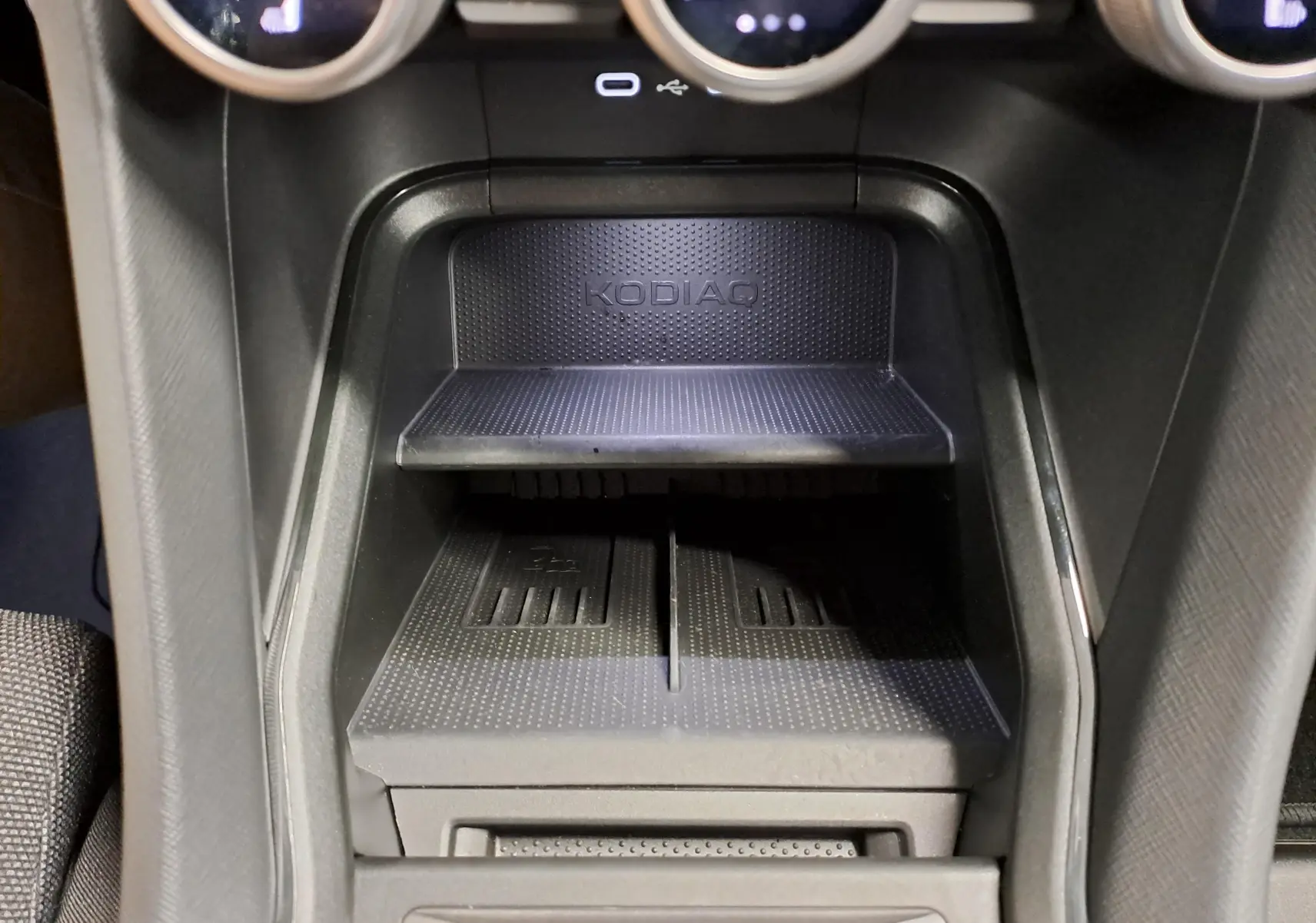 Gros plan sur la console centrale noire du Skoda Kodiaq 2025 avec espace de rangement marqué KODIAQ.