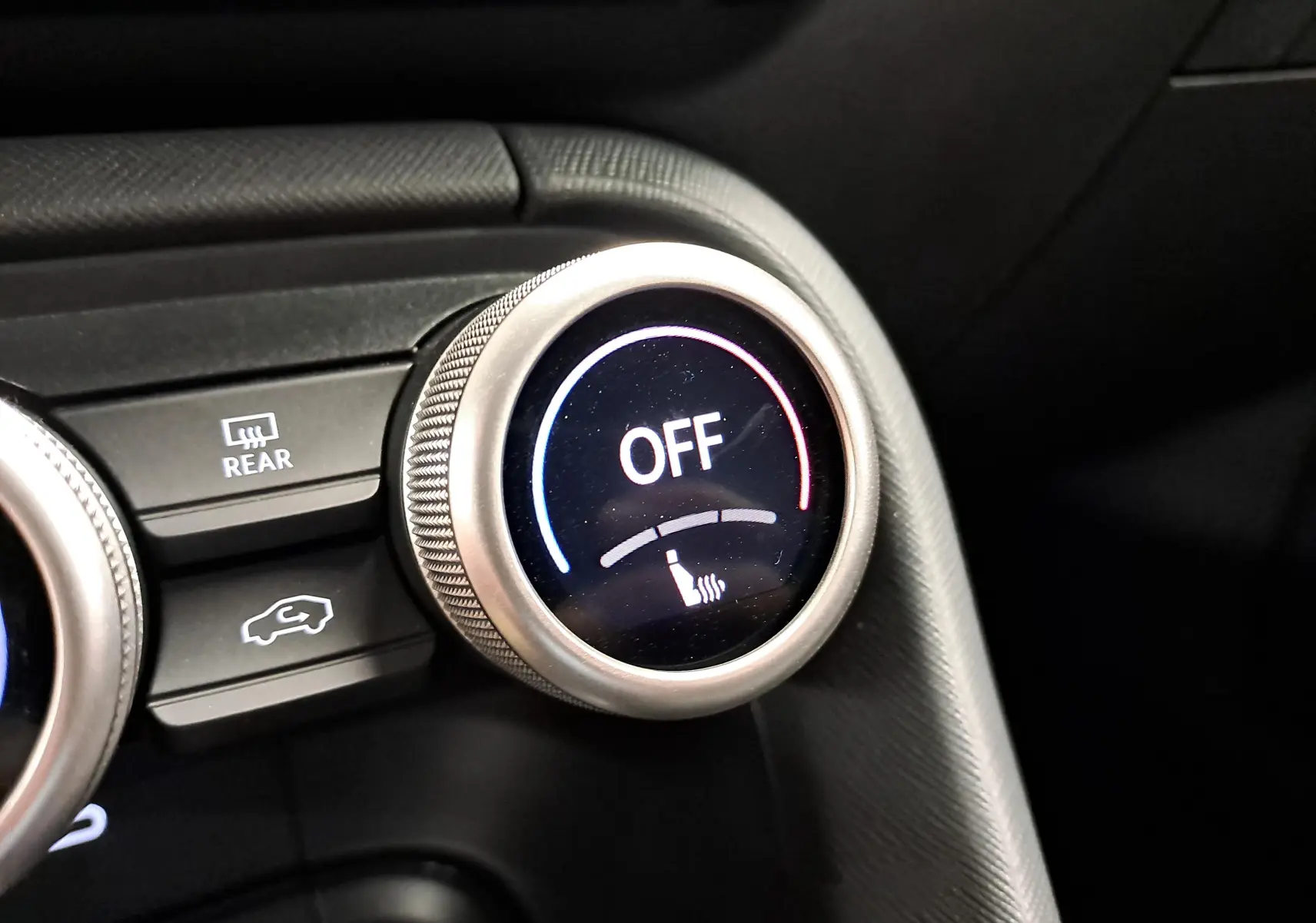 Gros plan sur le bouton de réglage du siège chauffant éteint dans l’habitacle du Skoda Kodiaq gris graphite.