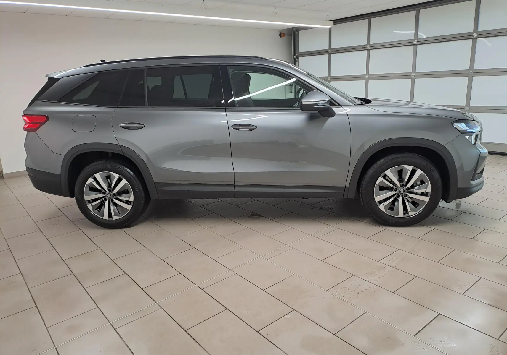 Vue de profil côté droit d'un Skoda Kodiaq 2025 gris graphite avec jantes alliage 18'' Soira anthracite et vitres surteintées.