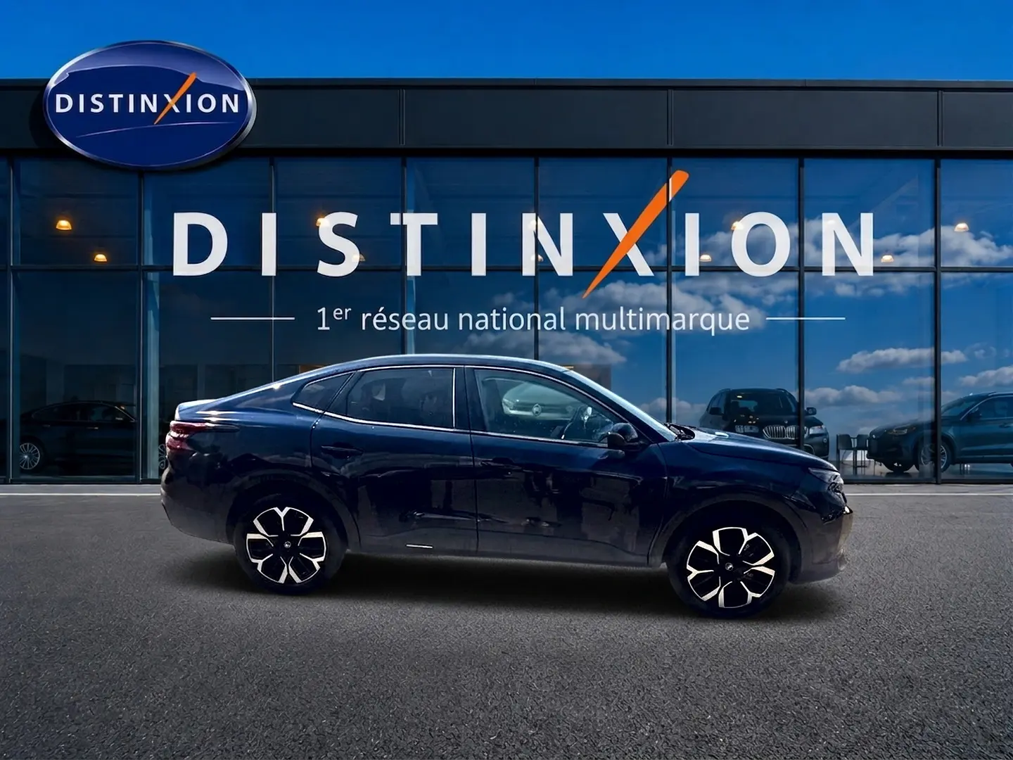 Vue de profil côté gauche d'une Citroën C4 X bleu foncé avec jantes alu devant une vitrine Distinxion.