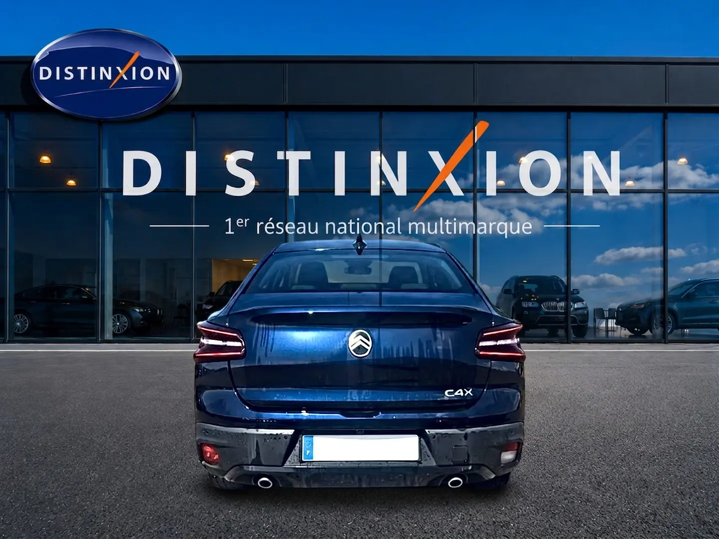 Vue arrière d'une Citroën C4 X bleu 2025 avec feux LED et double sortie d'échappement, devant une vitrine Distinxion.