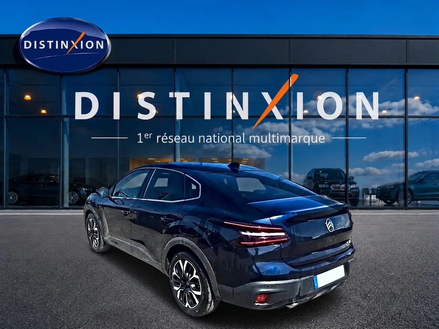 Vue 3/4 arrière droite d'une Citroën C4 X bleu foncé garée devant une concession Distinxion.