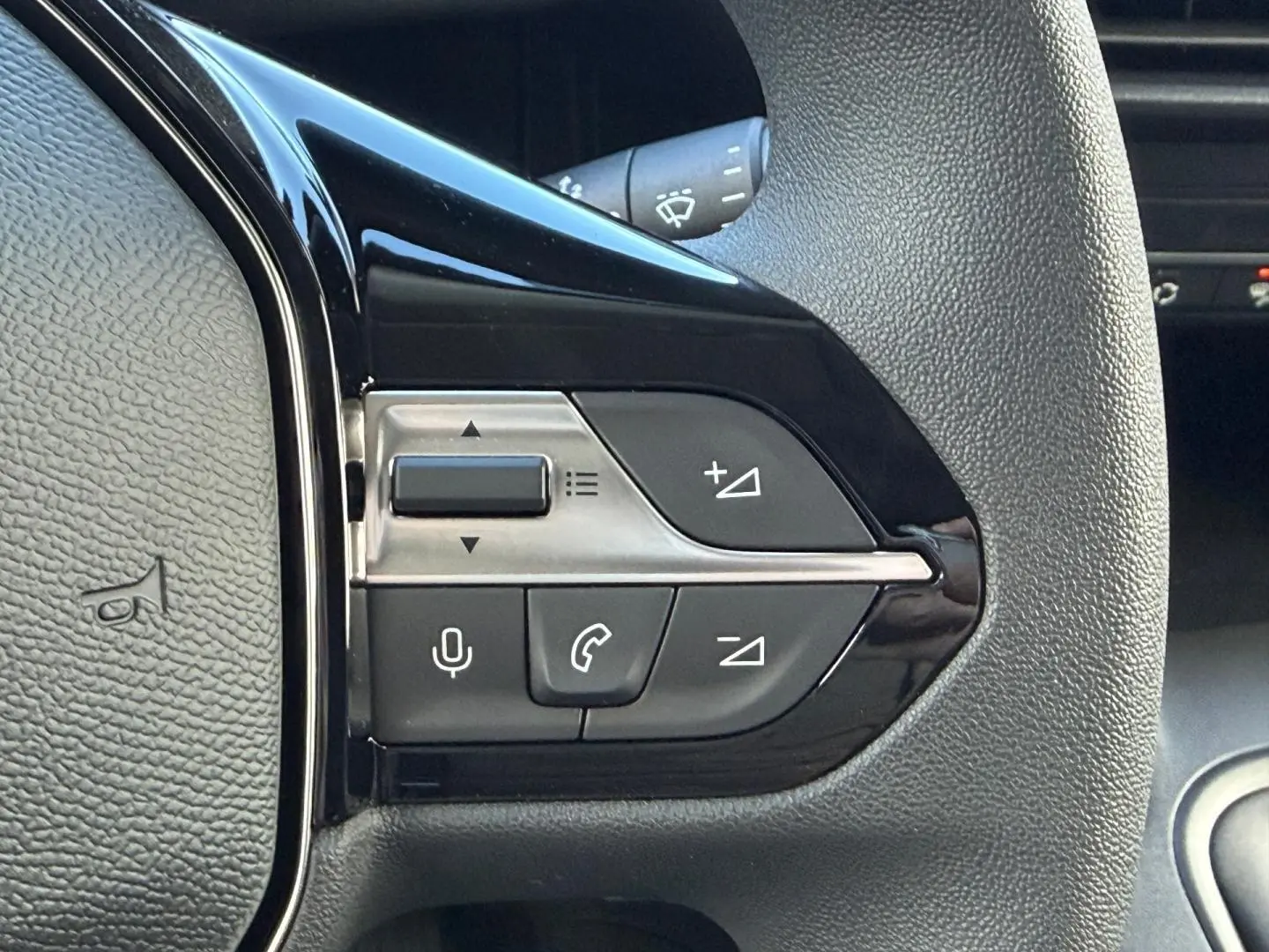 Gros plan sur les commandes multifonctions noires et argentées du volant du Peugeot Partner blanc Icy 2026.