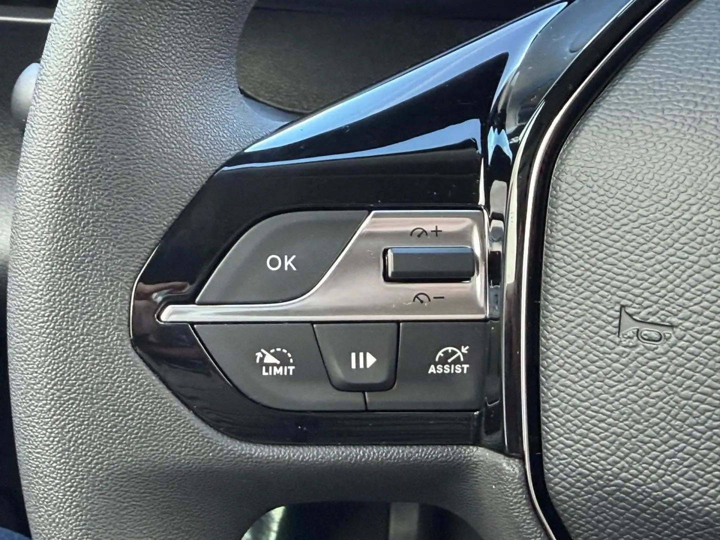 Gros plan sur les commandes de régulateur de vitesse au volant noir du Peugeot Partner blanc Icy 2026.