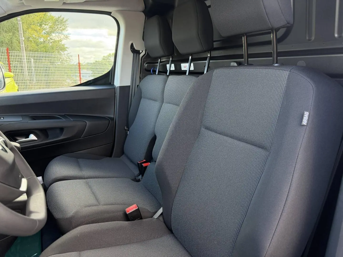 Vue intérieure côté conducteur du Peugeot Partner 2026, montrant la banquette avant 2 places en tissu gris Curitiba Triton Meltem.