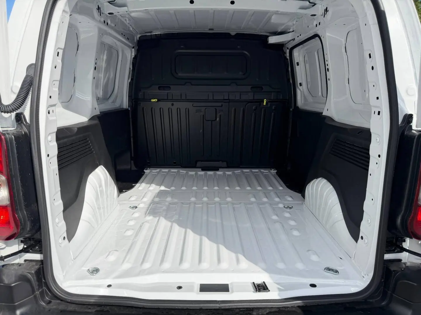 Vue arrière du coffre vide du Peugeot Partner blanc Icy, montrant l'espace de chargement et la cloison noire.