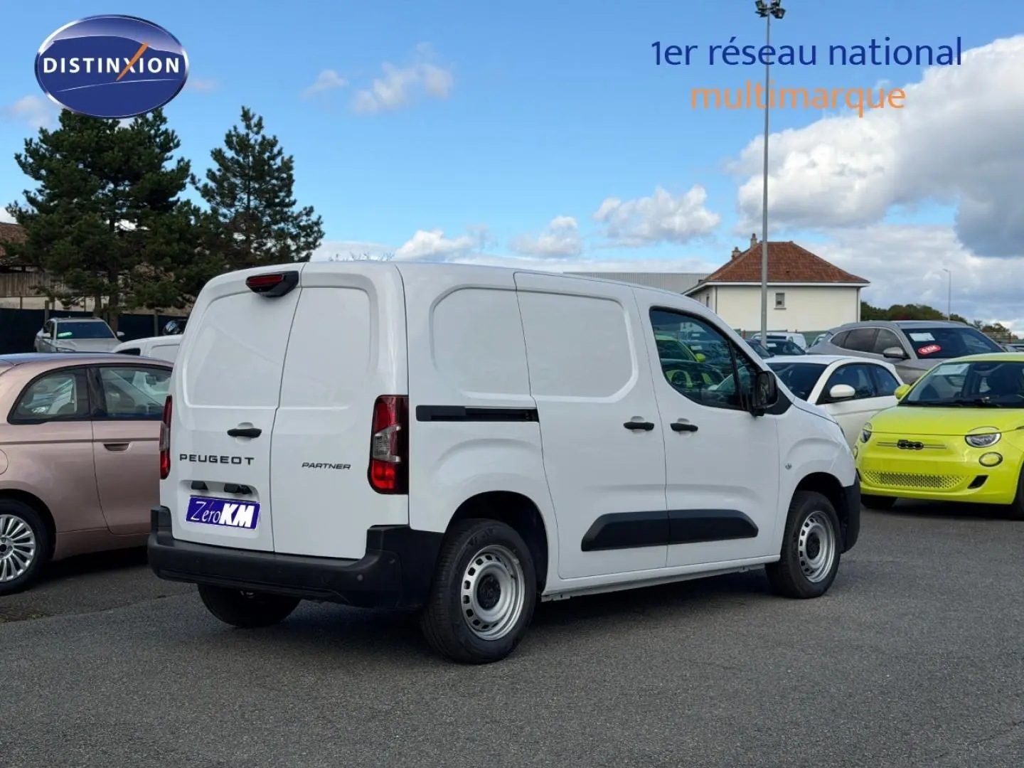 Vue 3/4 arrière droite d'un Peugeot Partner blanc Icy avec porte latérale coulissante, stationné en extérieur.