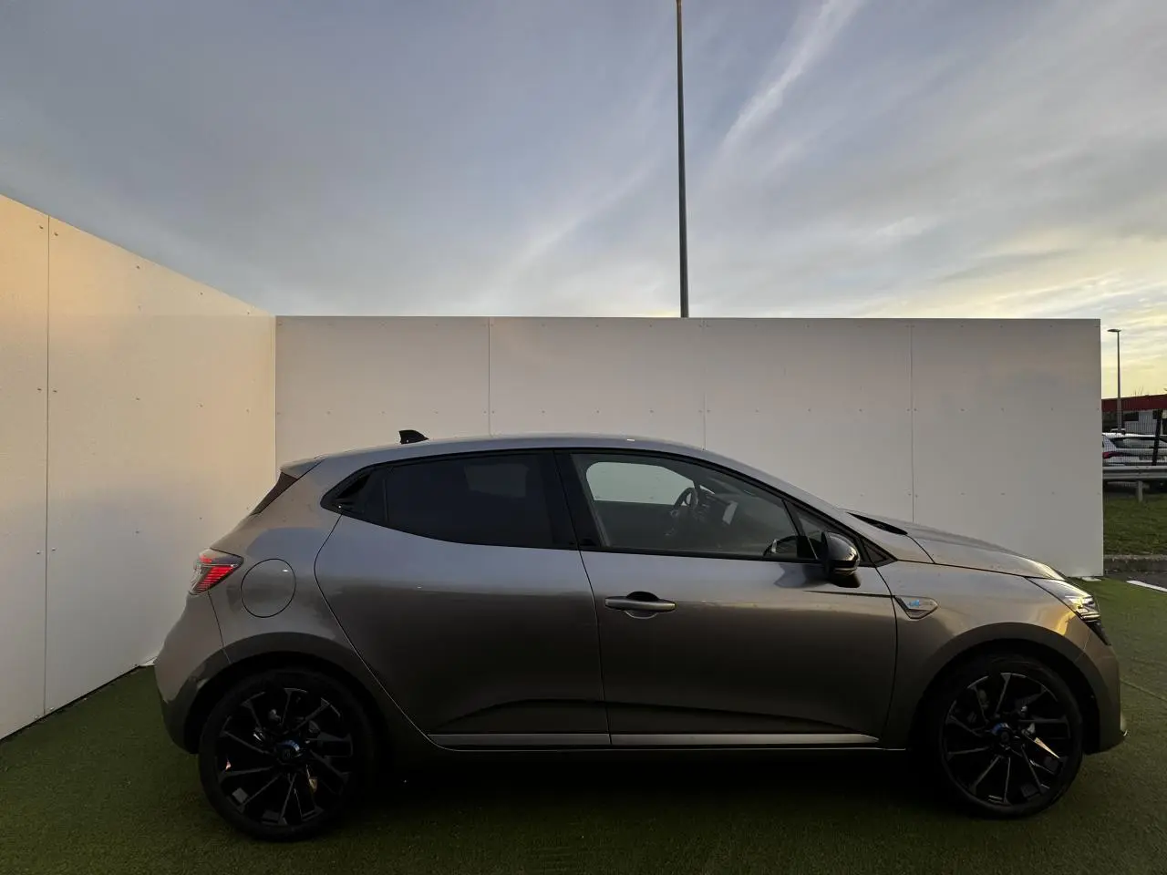 Renault Clio V hybride gris schiste vue de profil côté gauche, jantes alliage noires et vitres teintées.