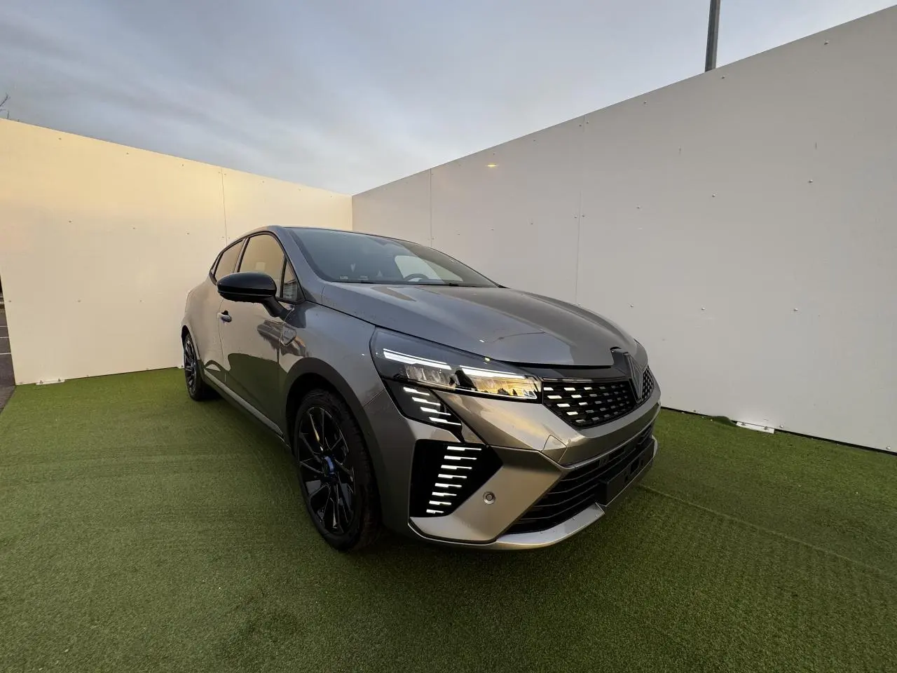 Renault Clio V hybride gris schiste métal vue 3/4 avant droit avec feux LED et jantes noires distinctives.