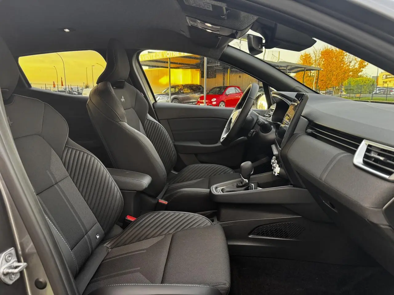 Vue intérieure côté conducteur de la Renault Clio gris schiste avec sièges sport noirs et volant multifonction