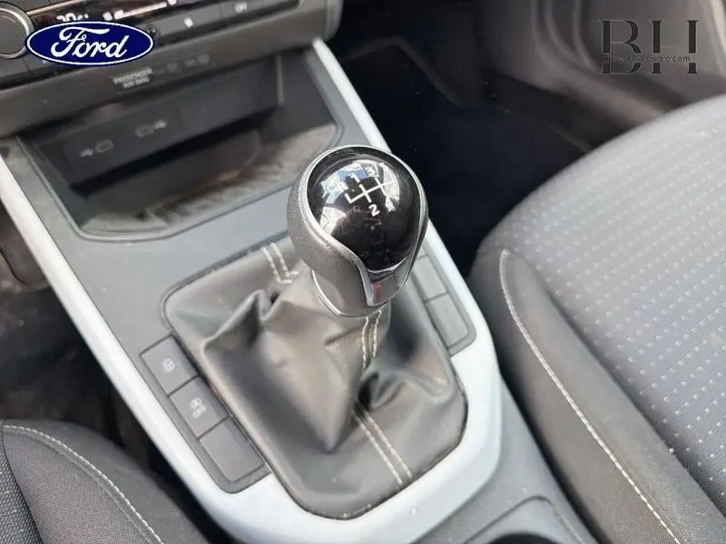 Gros plan sur levier de vitesses manuel noir avec coutures blanches dans l'habitacle d'une SEAT Arona Gris Urbain Métal 2022.