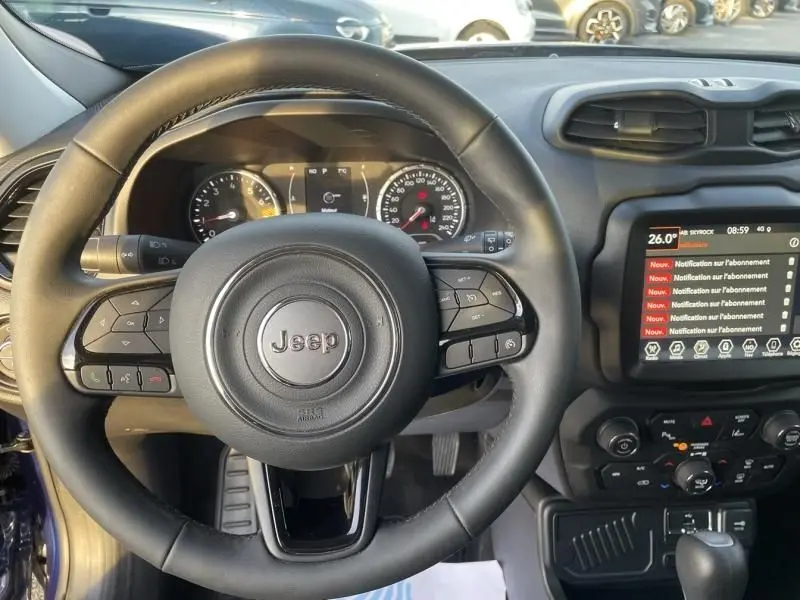 Vue intérieure centrée sur le volant noir du Jeep Renegade bleu Jetset Metal avec tableau de bord et écran tactile.