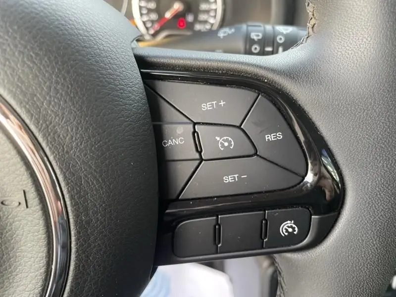 Gros plan sur les commandes de régulateur de vitesse à droite du volant d'un Jeep Renegade 2021, intérieur noir.