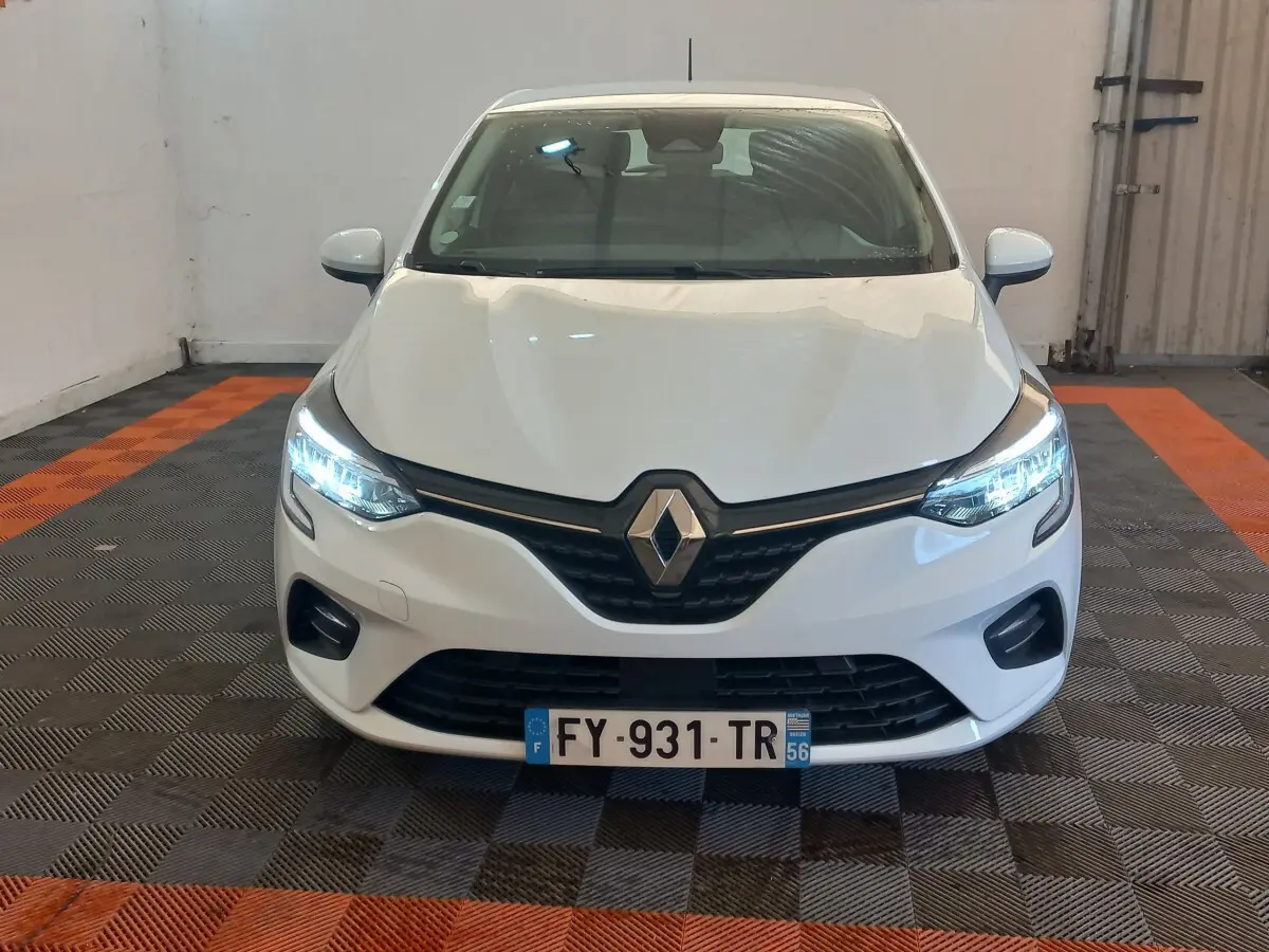 Vue frontale d'une Renault Clio Business blanche avec phares LED allumés dans un garage.