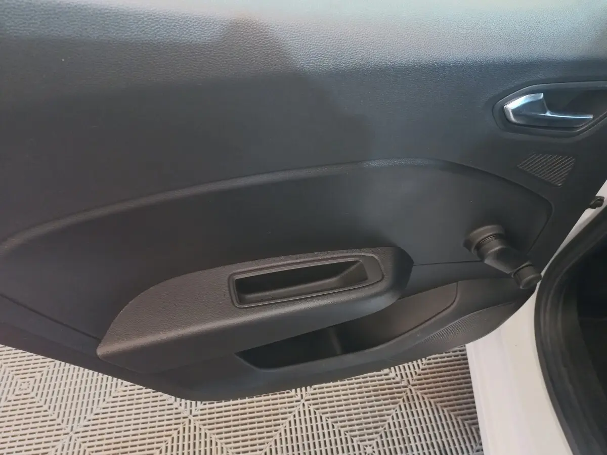 Vue intérieure côté gauche de la porte avant d'une Renault Clio Business blanche avec manivelle de vitre manuelle.