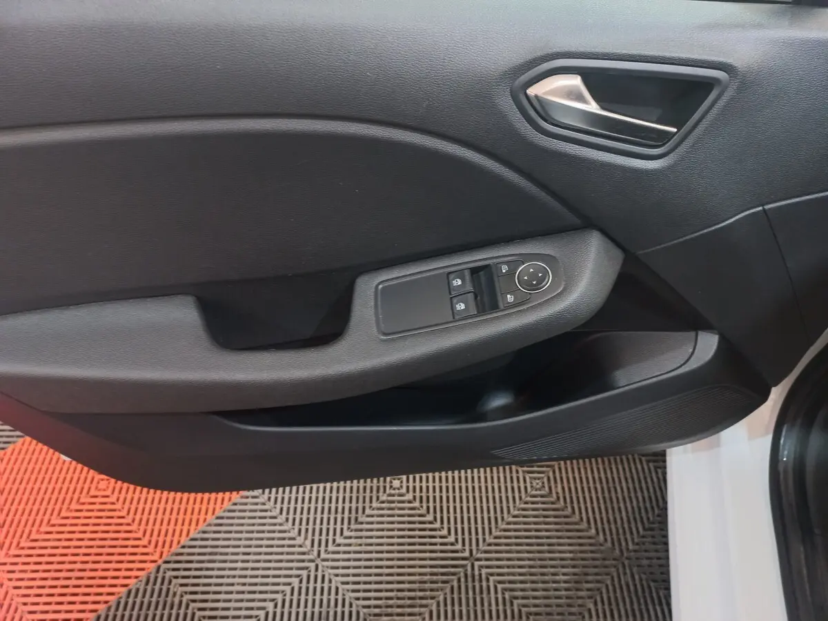 Vue rapprochée de la porte avant gauche noire de la Renault Clio Business blanche, avec commandes électriques et poignée argentée.