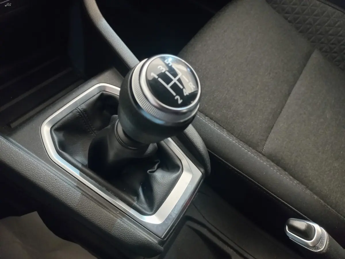 Gros plan sur le levier de vitesses manuel noir et argenté de la Renault Clio Business, avec siège tissu gris à côté.