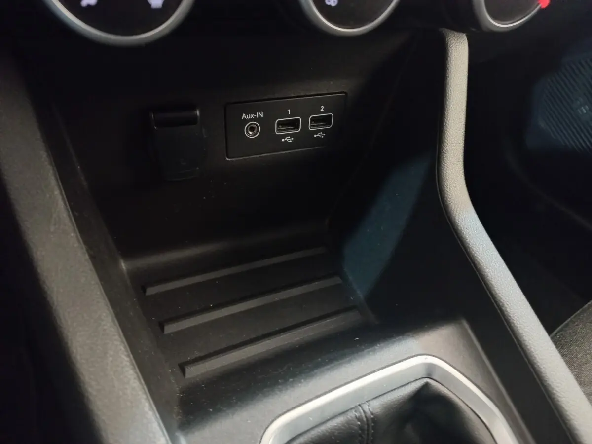 Vue intérieure rapprochée du port USB et prise Aux-IN noirs sur la console centrale d'une Renault Clio blanche.