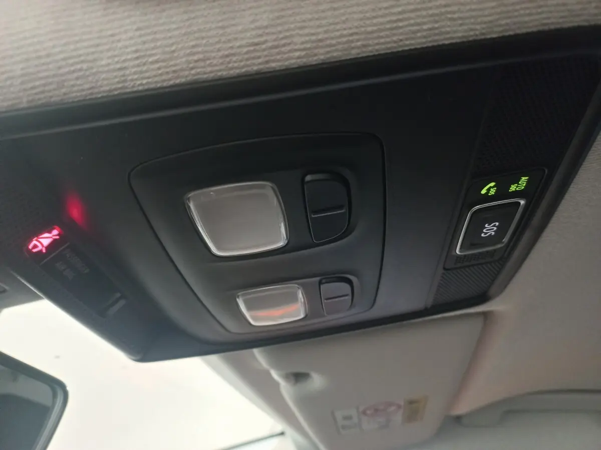 Plafonnier intérieur avec commandes d’éclairage et bouton SOS activé dans une Renault Clio blanche, vue vers l’avant.