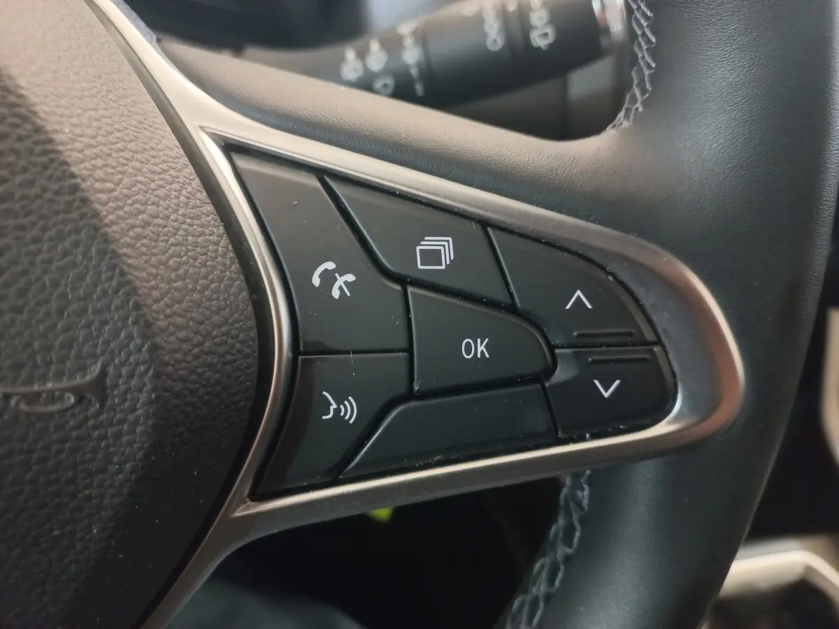 Gros plan sur les commandes multifonctions du volant cuir synthétique de la Renault Clio Business blanche, version 2021.