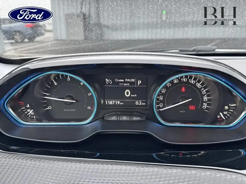 Tableau de bord Peugeot 2008 blanc Banquise vu de face, affichage numérique et compteurs analogiques éclairés en bleu.