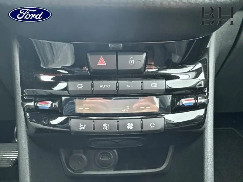 Console centrale vue de face avec commandes de climatisation automatique et boutons de verrouillage, finition noire brillante.