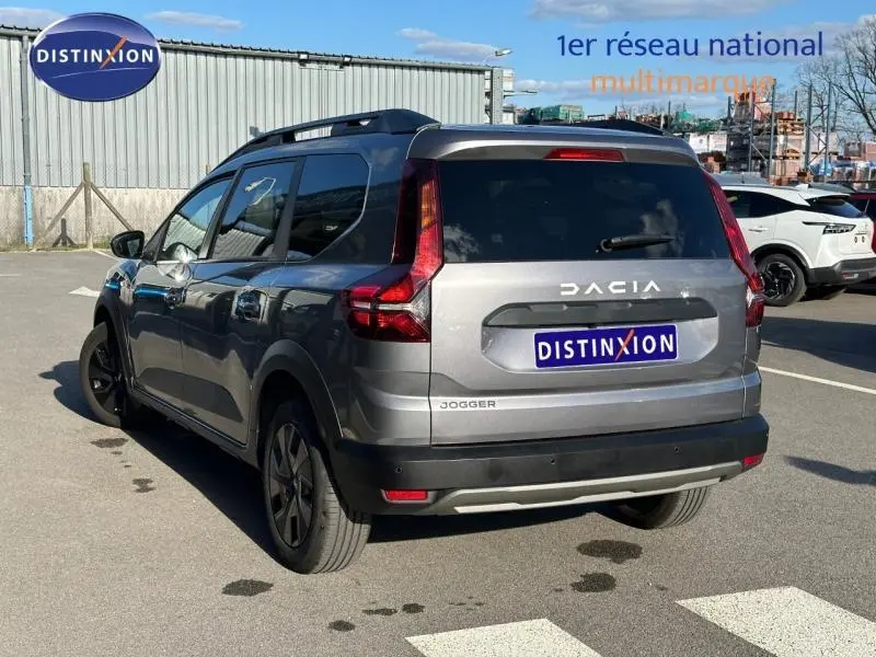Vue 3/4 arrière droite d'un Dacia Jogger gris schiste métallisé, version 7 places avec toit noir et feux arrière verticaux.