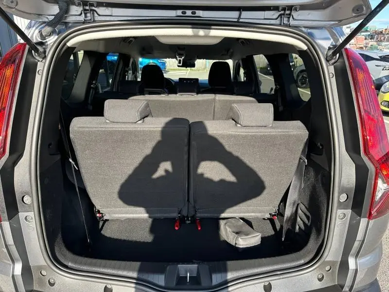 Vue arrière ouverte du coffre du Dacia Jogger gris schiste métallisé, montrant la troisième rangée de sièges relevée et l'habitacle intérieur.