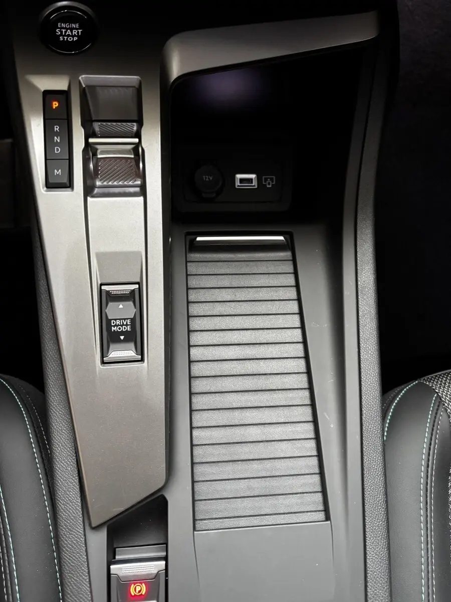 Vue rapprochée de la console centrale intérieure de la Peugeot 308 Hybrid 145 e-DCS6 Allure avec commandes de boîte auto et frein à main électrique.