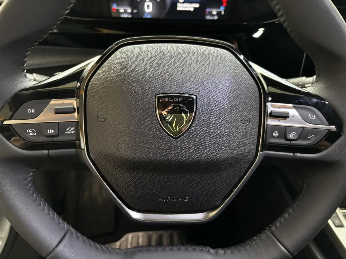 Gros plan sur le volant cuir noir multifonctions de la Peugeot 308 Hybrid 145 e-DCS6 Allure 2025.