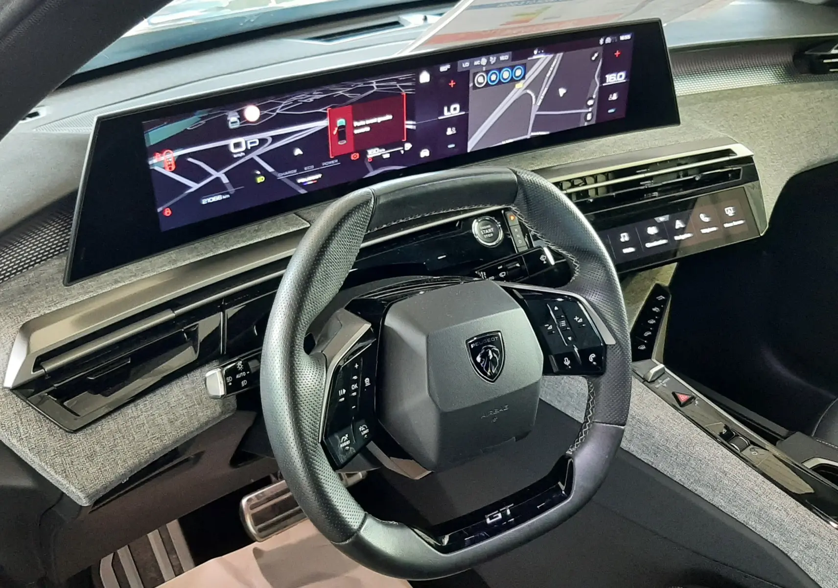 Vue intérieure du poste de conduite du Peugeot 3008 Hybrid GT 2025, volant cuir noir et écran digital panoramique.