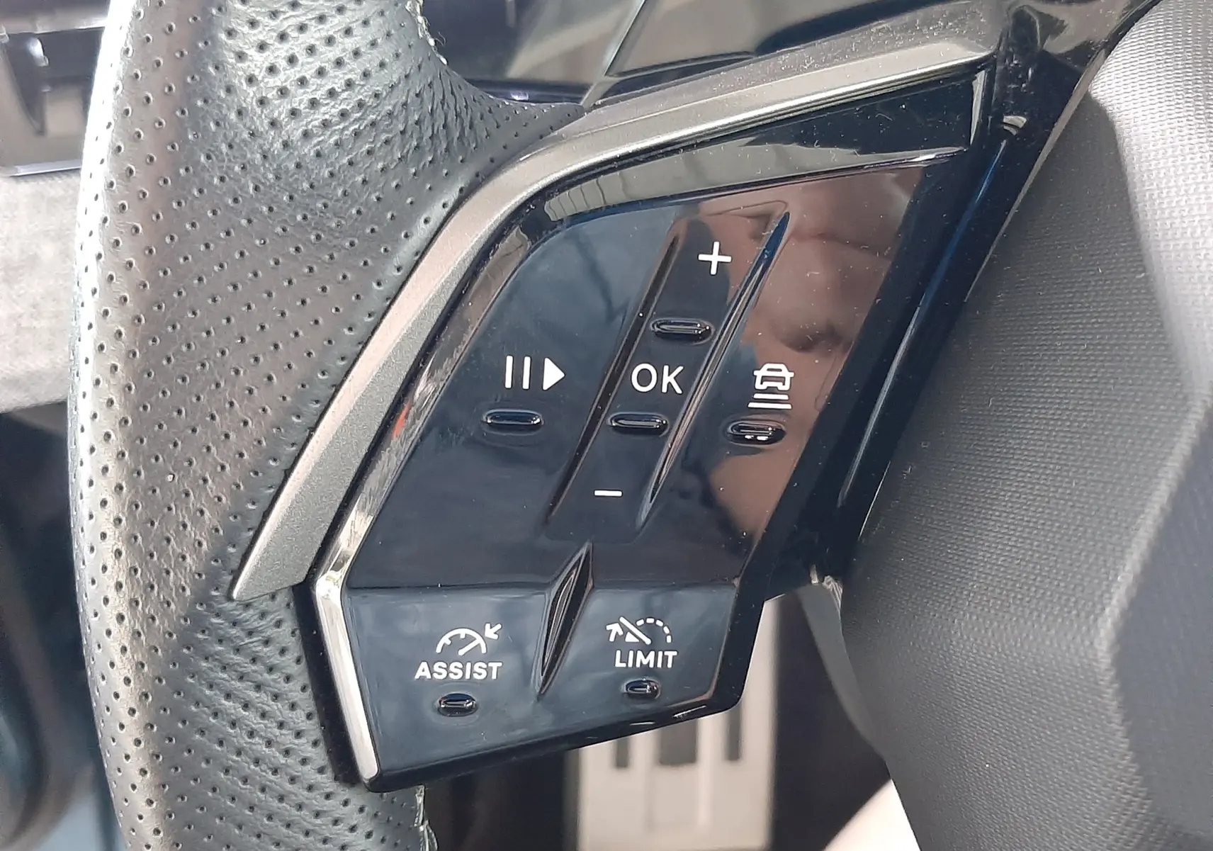 Gros plan sur les commandes à gauche du volant perforé du Peugeot 3008 bleu Ingara, avec boutons de régulateur et assistances.