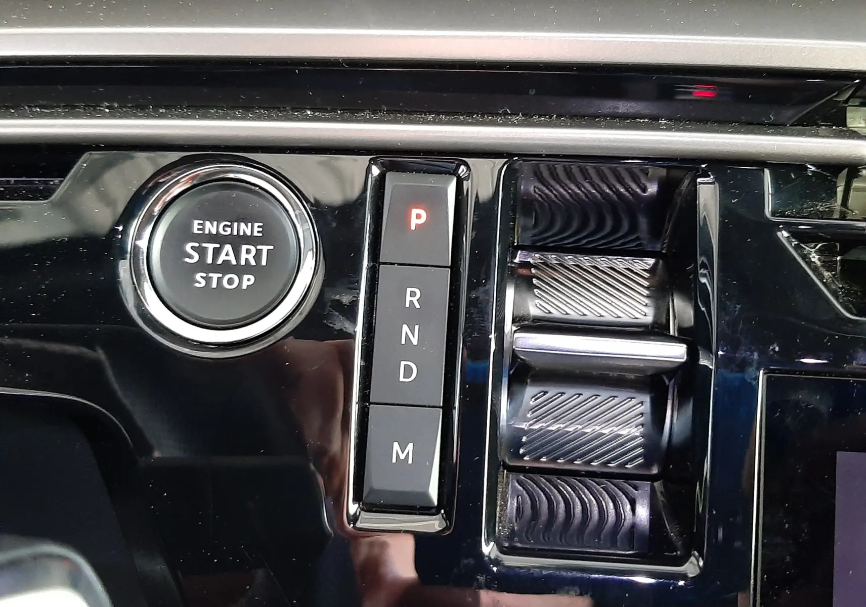 Détail de la console centrale du Peugeot 3008 hybride 2025, avec bouton start/stop et commandes de boîte auto en noir brillant.