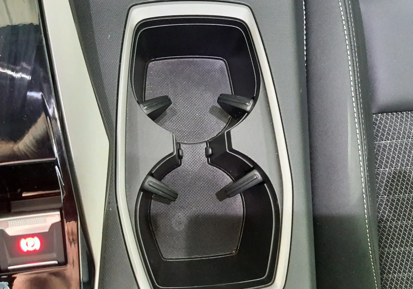 Gros plan sur les porte-gobelets centraux et accoudoir en cuir noir du Peugeot 3008 Hybrid 2025.